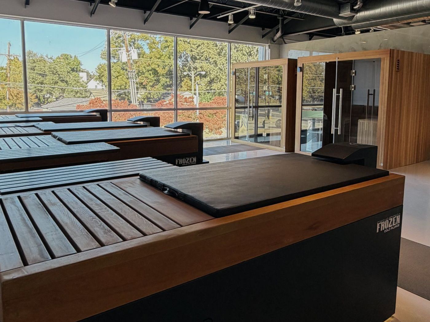 Row of cold plunge tubs by the front windows at Vital Athletic Recovery, with the saunas behind them